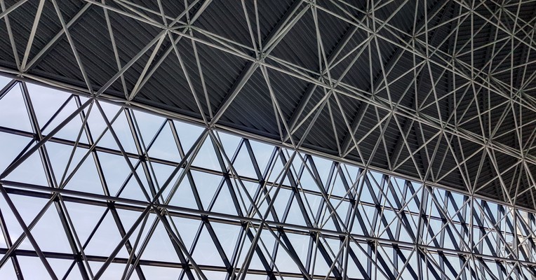 AI deployment testing: the triangulated steel frame of a terminal roof, every member carrying a checked load