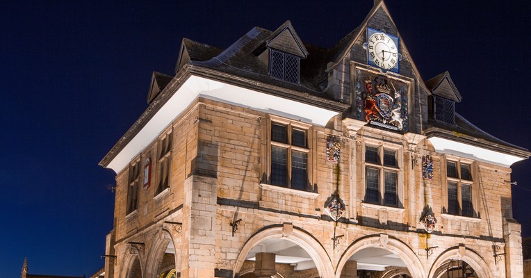 AI governance migrating to IT: Peterborough Guildhall floodlit against a deep blue night sky