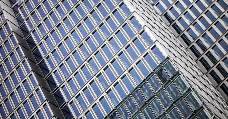 AI objective drift: a dark glazed tower facade receding at an angle, its lines pulling away from the viewer