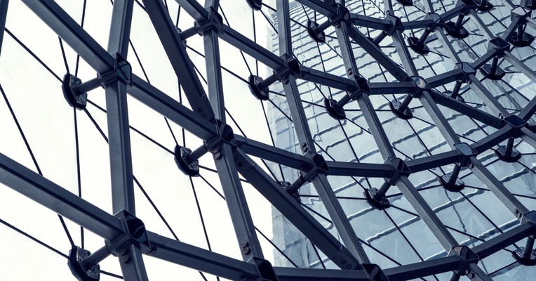 AI supplier questionnaires: a curved glass facade on steel spider fittings, each fixing point open to inspection