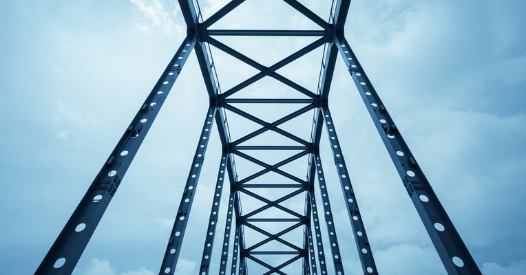 AI supply chain security: a steel bridge truss against a pale sky, each member depending on the one below it