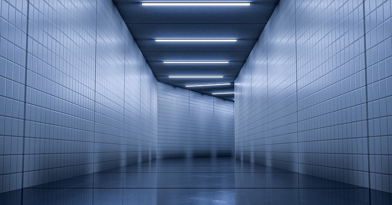 AI test environment separation: an empty blue tiled corridor under strip lighting, closed at the far end